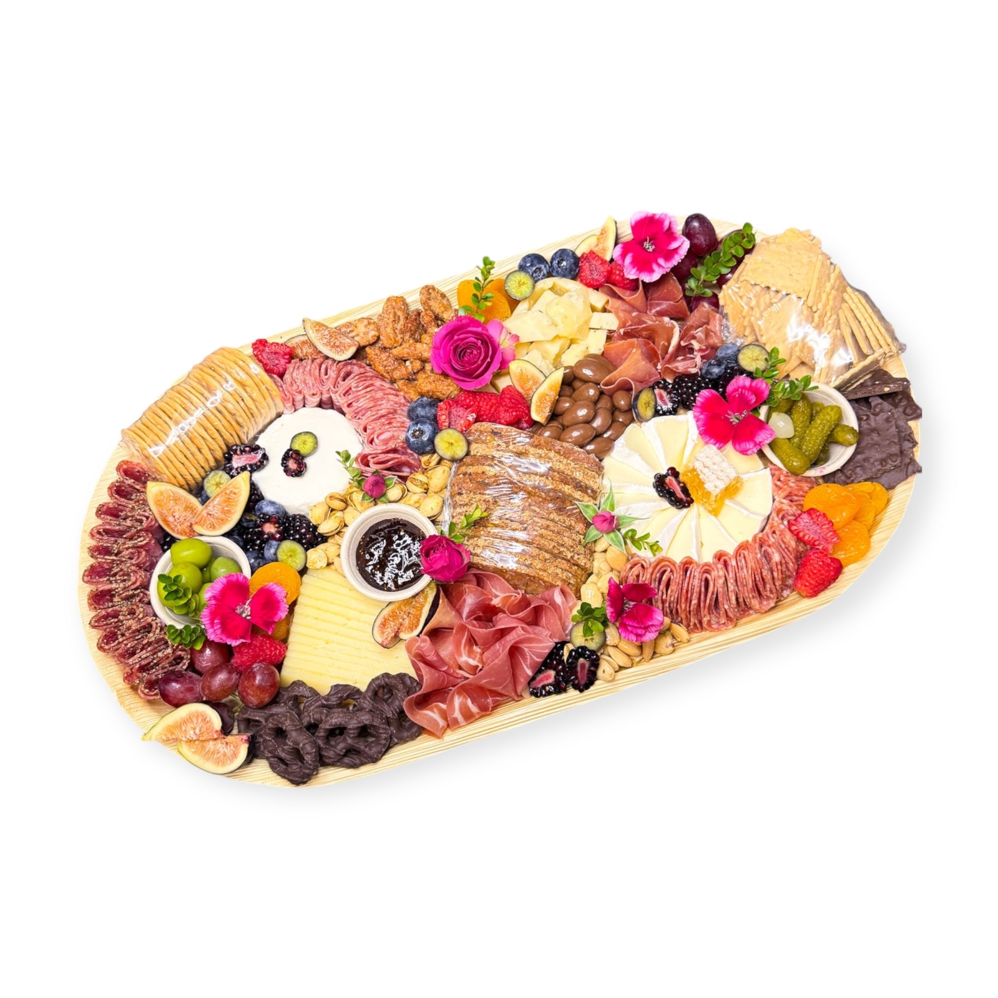 Family charcuterie platter with artisan cheeses, cured meats, fruit, nuts, olives, crackers, and chocolates arranged with floral accents.