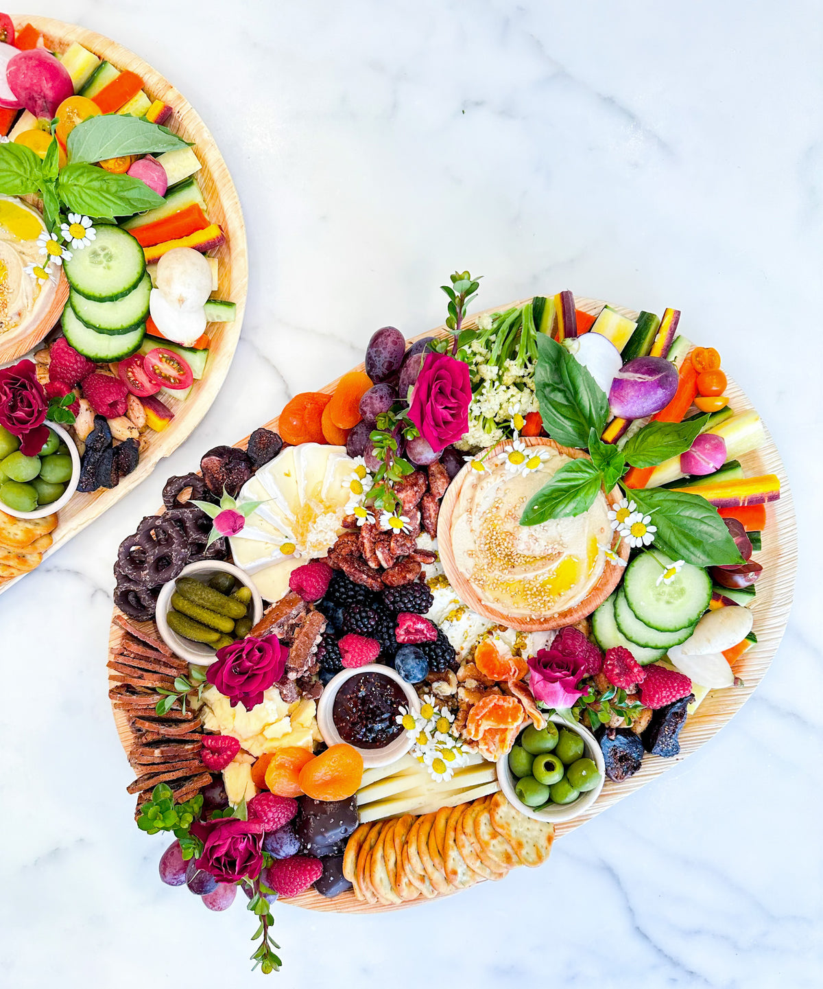 Vegetarian charcuterie platter with fresh vegetables, hummus, cheeses, fruits, olives, and crackers, styled by Newport Charcuterie.